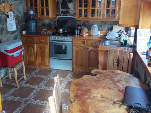 cocina con armarios de madera, fogones y mesa en CASA TRIBU, en San Antonio Palopó