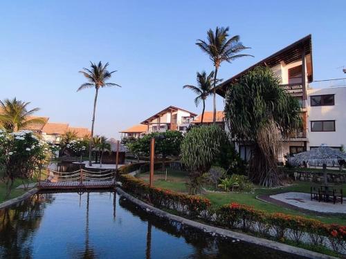 São Gonçalo do Amarante的住宿－Casa em resort na Taiba，棕榈树建筑前的河流