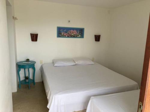 1 dormitorio con cama blanca y mesa azul en Casa em resort na Taiba, en São Gonçalo do Amarante