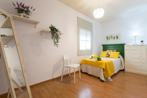 Un dormitorio con una cama con almohadas amarillas y una silla en Centrico Tranquilo 2 Rooms, en Jerez de la Frontera