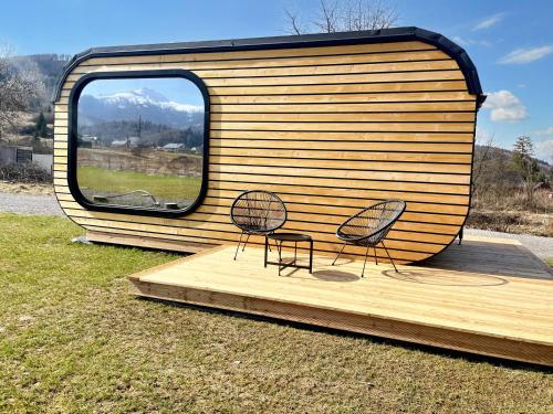 two chairs sitting on a wooden deck next to a trailer at Domček Artemis in Zuberec