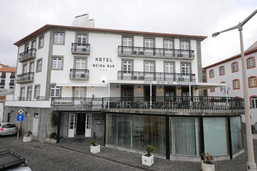 a large white building with balconies on a street at Hotel Beira Mar in Angra do Heroísmo