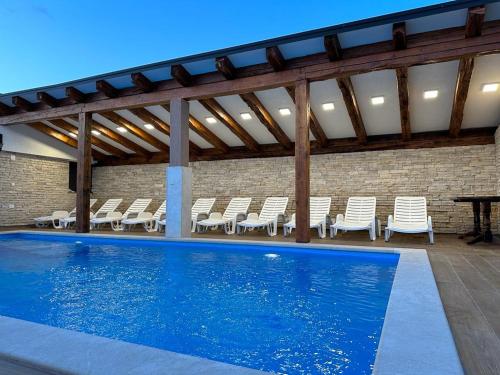 a large swimming pool with chairs and a table at Holiday Home Robert 2 with pool in Cesarica