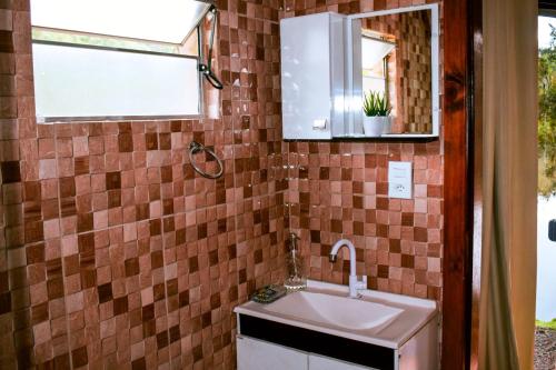 a bathroom with a sink and a mirror at Oásis Pousada in Cambará