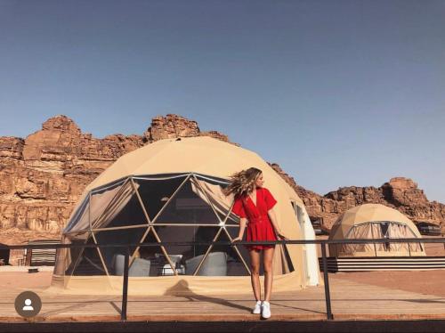 a woman in a red dress standing in front of a tent at RUM MAGiC lUXURY CAMP in Wadi Rum