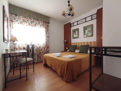 a bedroom with a bed and a window and a table at HOSTAL RURAL ALTO TAJO POVEDA in Poveda de la Sierra