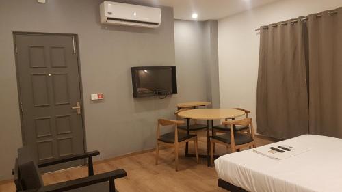 a room with a table and a bed and a tv at TREETOP INN in Chennai