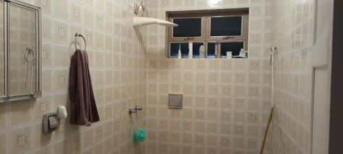 La salle de bains carrelée est pourvue d'une douche et d'une fenêtre. dans l'établissement Pousada e Hostel Sossego, à Luminárias