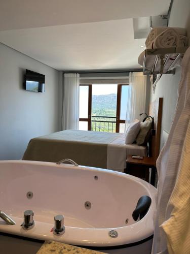 a bathroom with a bath tub and a bed at Pousada Maria Monteiro Tiradentes in Tiradentes