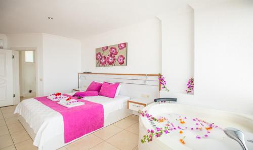 a white bedroom with two beds with pink accents at Villa Eslem in Kas