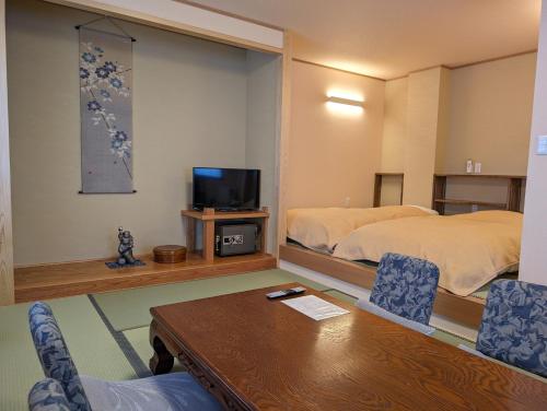 a hotel room with a table and a bed and a tv at Oyado Nozawaya in Nozawa Onsen