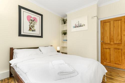 a bedroom with a white bed with a wooden door at Very Central - Comfy & Quiet In Westminster For 4 in London