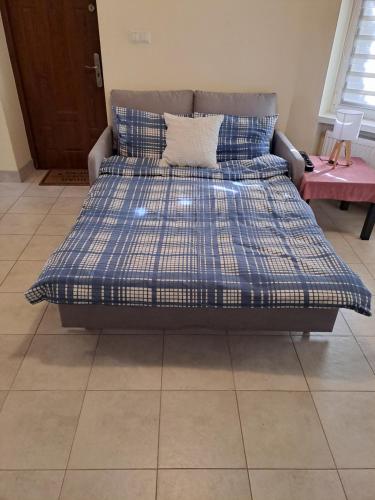 a bed with a blue and white bedspread on it at Mały domek - Zielonka in Zielonka