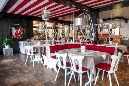 a dining room with white tables and red chairs at Schwanen-Resort in Baiersbronn