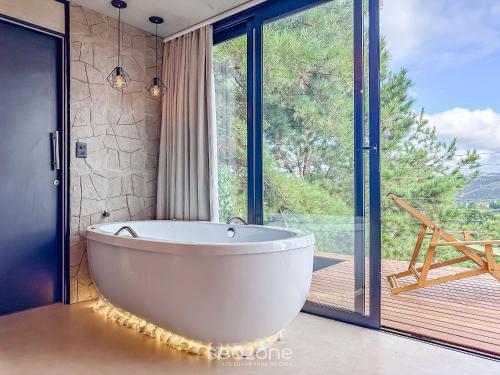 une baignoire dans une salle de bain avec une grande fenêtre dans l'établissement CNB - Cabanas Vista Serra em Campos do Jordão, à Campos do Jordão