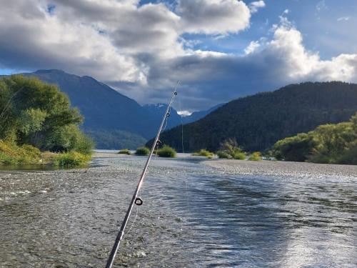 a fishing pole in the water on a river at Cabañas Los Lúpulos in El Bolsón