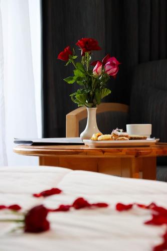 a table with a vase of flowers and a plate of food at Bizerta Resort Congres & SPA in Bizerte