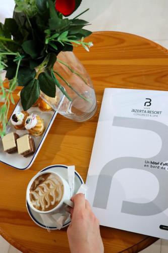 a table with a cup of coffee and a book at Bizerta Resort Congres & SPA in Bizerte