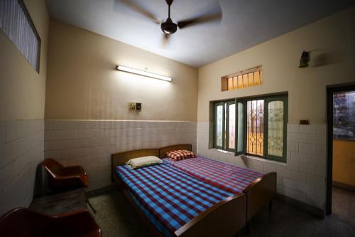 a bed in a room with a ceiling fan at Sri sai baba guest house in Pondicherry