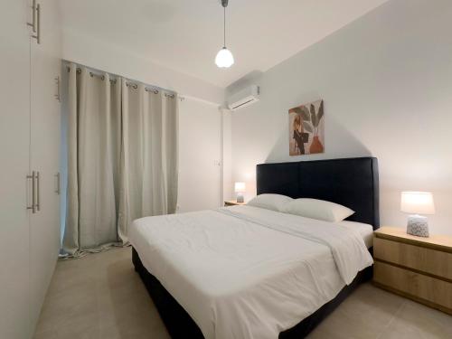 a white bedroom with a large bed and two lamps at Glenvar Heights A2 Spacious apt in Paleo Faliro in Athens