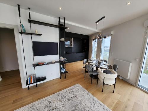 - un salon avec une table, des chaises et une télévision dans l'établissement Le Davs - Splendide appartement avec vue, à Caen