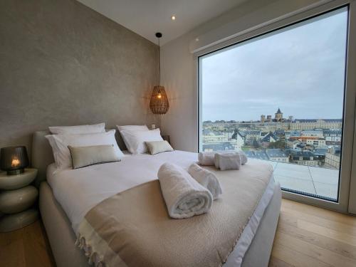 une chambre avec un grand lit avec une grande fenêtre dans l'établissement Le Davs - Splendide appartement avec vue, à Caen