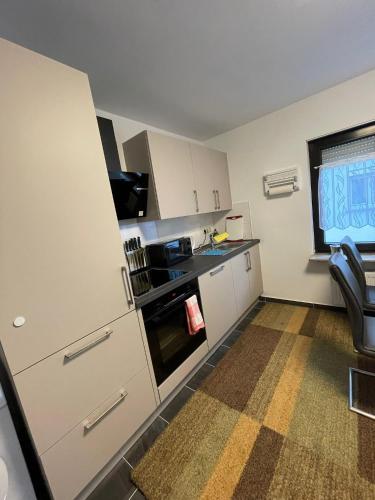 a small kitchen with white cabinets and a window at Luis Zimmer Wohnung Rüsselsheim O1 in Haßloch