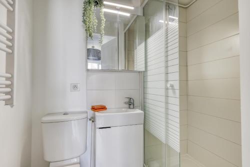 a white bathroom with a toilet and a sink at Branded New Cozy Studio in the Heart of Paris 17 in Paris