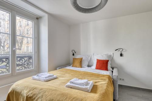 a white bedroom with a bed with towels on it at Branded New Cozy Studio in the Heart of Paris 17 in Paris
