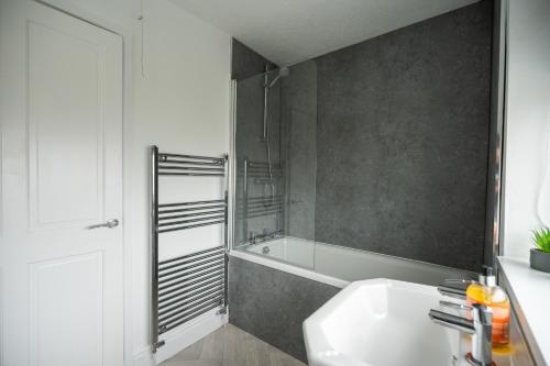 a bathroom with a tub and a sink and a shower at Renvyle House By Horizon Stays in Stockton-on-Tees