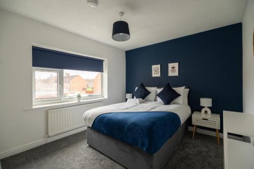 a bedroom with a bed with blue walls and a window at Renvyle House By Horizon Stays in Stockton-on-Tees