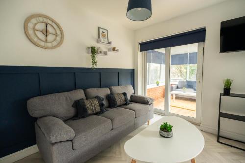 a living room with a couch and a table and a clock at Renvyle House By Horizon Stays in Stockton-on-Tees