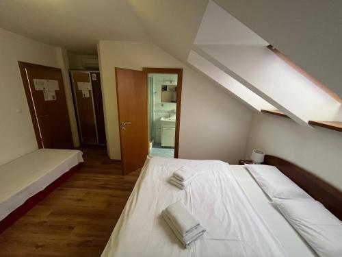 a bedroom with a bed with white sheets and towels at Penzión a Reštaurácia Harmónia Ostratice in Malé Ostratice