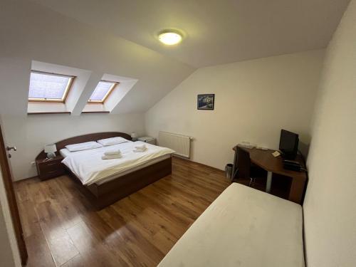 a bedroom with a bed and a desk with a television at Penzión a Reštaurácia Harmónia Ostratice in Malé Ostratice