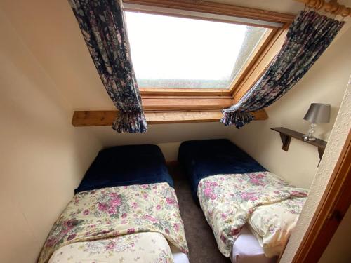 two beds in a small room with a window at Bellfield Country Suites in Masham