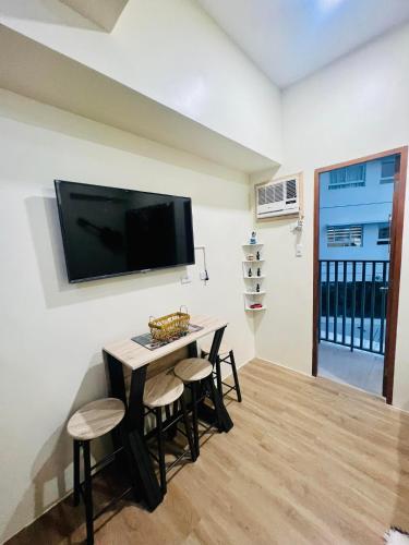 uma sala de estar com uma mesa e bancos com uma televisão na parede em Northwoods Place em Mandaue