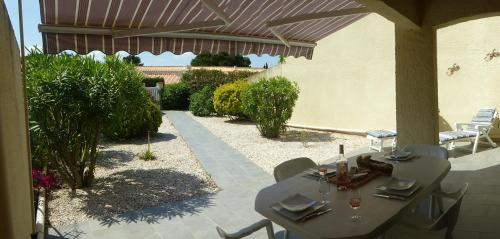 - une table et des chaises sous un parasol sur la terrasse dans l'établissement Maison de vacances St Cyprien Plage, à Saint-Cyprien