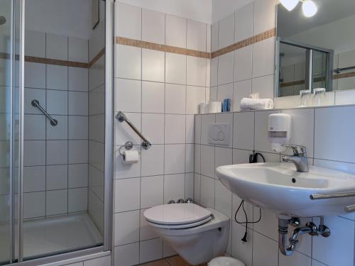 ein Bad mit einem WC, einem Waschbecken und einer Dusche in der Unterkunft Zeitlos Hotel Garni in Scharbeutz
