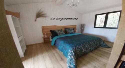een slaapkamer met een bed met een blauw dekbed bij La Bergeronnette in Queyrac