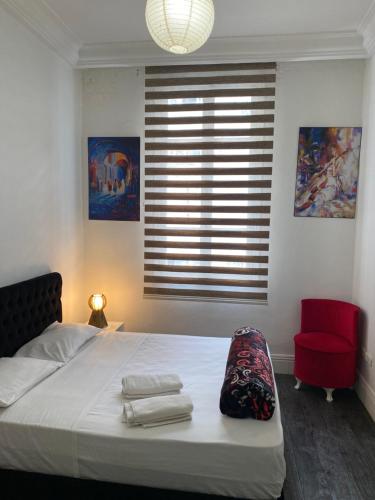 ein Schlafzimmer mit einem Bett, einem roten Stuhl und einem Fenster in der Unterkunft Tunis Lafayette in Tunis