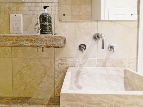 a bathroom with a sink and a bottle on a counter at Primrose Cottage in Emsworth