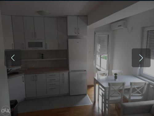- une cuisine avec des placards blancs, une table et des chaises dans l'établissement Apartman KoprenaZ, à Banja Luka