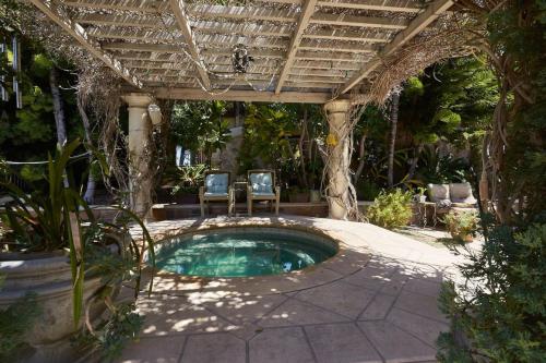 una piscina en un patio con 2 sillas bajo una pérgola en UNEQUALLED LUXURY VILLA BEACH 7000ft 180 VIEW en Laguna Beach