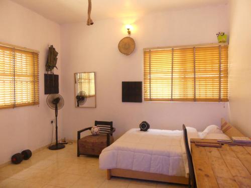 a bedroom with a bed and a chair and windows at Templar's Court in Port Harcourt