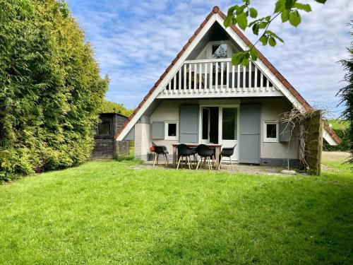 a white house with chairs and a table in the yard at Olivia 6pers House with a private garden close to the National Park Lauwersmeer in Anjum