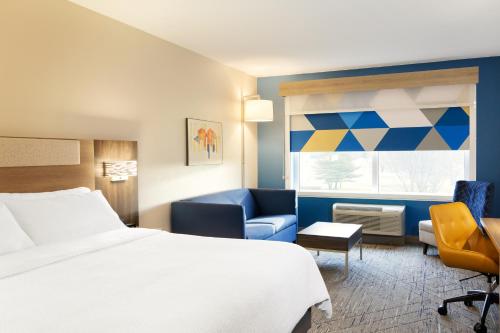 ポート・ワシントンにあるHoliday Inn Express & Suites Port Washington, an IHG Hotelのベッド1台、椅子、窓が備わる客室です。