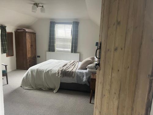 a bedroom with a bed with white sheets and a window at Moulin Cottage in Moulin