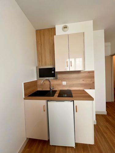 a kitchen with white cabinets and a sink at T2 4 pers face gare SNCF Appart Hotel le Cygne D3 in Bourges