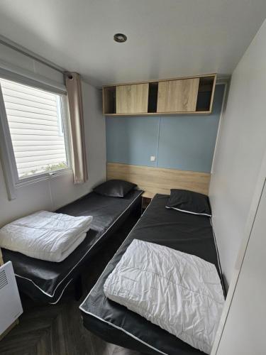 deux lits dans une petite pièce avec une fenêtre dans l'établissement Magnifique Mobil home climatisé (139), à Saint-Jean-de-Monts