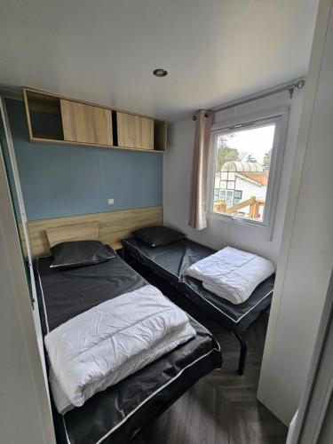 deux lits dans une petite pièce avec une fenêtre dans l'établissement Magnifique Mobil home climatisé (139), à Saint-Jean-de-Monts